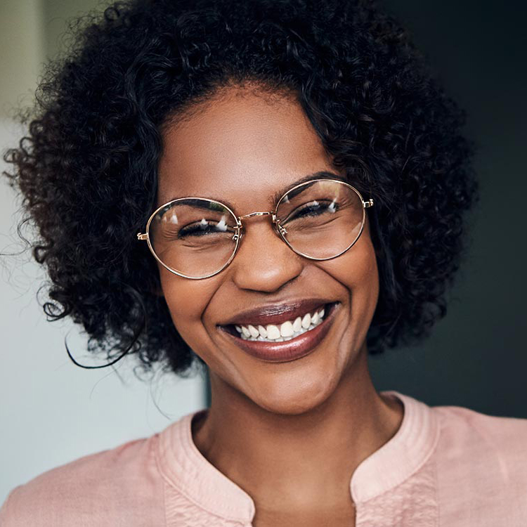 stock-photo-young-african-businesswoman-wearing-glasses-and-laughing-while-standing-alone-in-a-modern-office-1043390350 face of a smiling woman