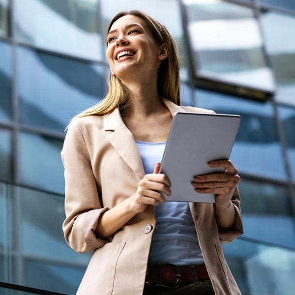 stock-photo-portrait-of-a-successful-business-woman-using-digital-tablet-in-front-of-modern-business-building-2049645026 smiling professional woman outside an office building
